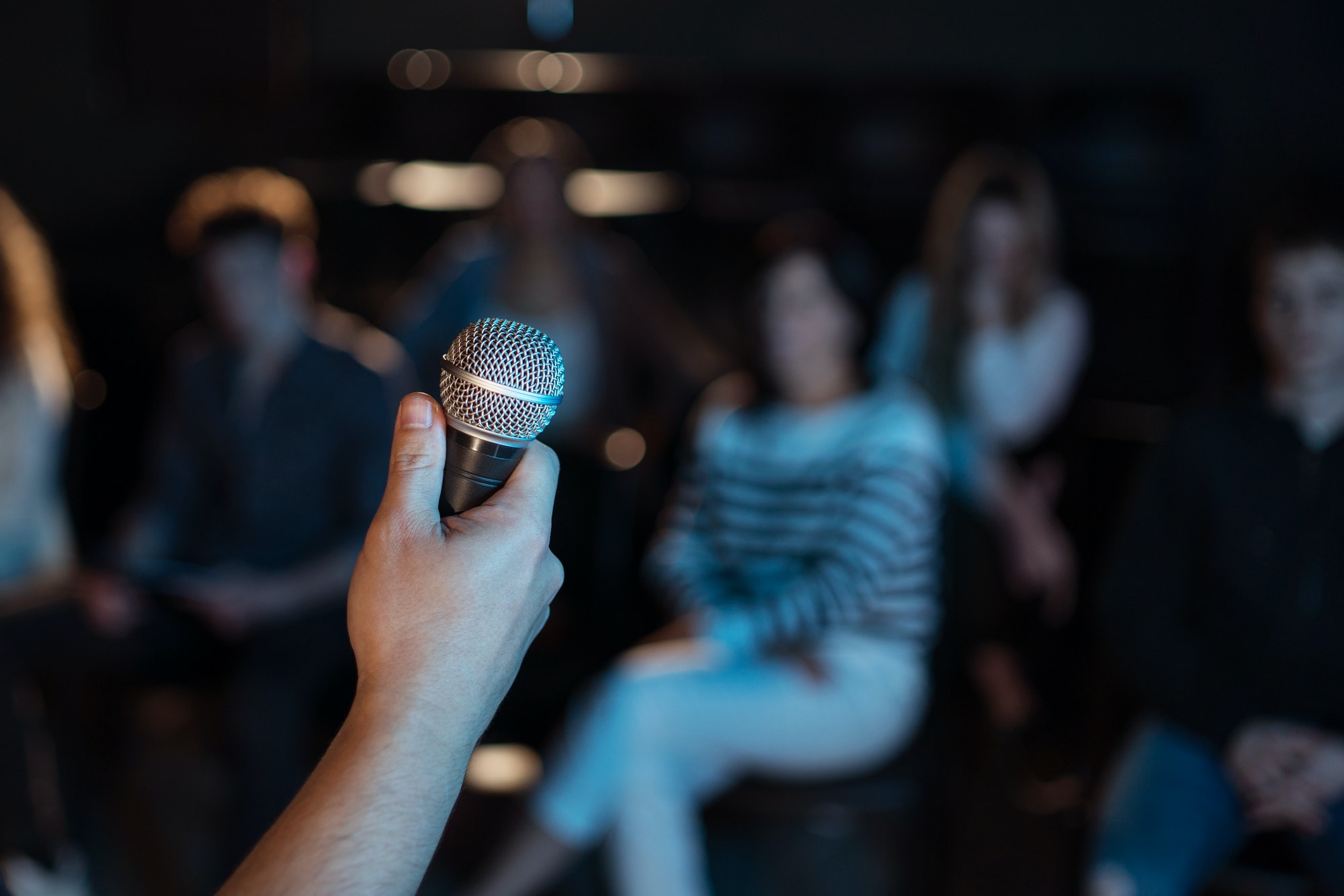 obscured-presenter-holding-microphone-presentation-at-conference-concept.jpg